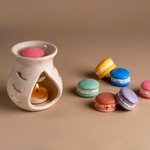 Load image into Gallery viewer, Ceramic oil burner with candle and colorful macarons on beige background