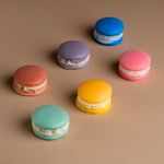 Load image into Gallery viewer, Colorful macarons with cream filling on a beige background, assorted pastel bakery cookies