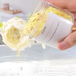 Load image into Gallery viewer, Hand pouring Amaraa Relax Unwind peppermint bath salt into water with white flower