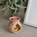 Load image into Gallery viewer, Ceramic wax melt burner with lit tealight and pink wax melt on beige table, leafy decor