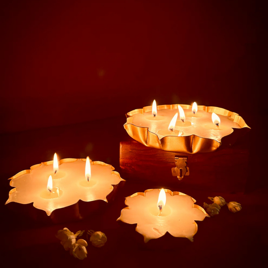 Lotus-shaped brass candles with multiple flames on a wooden box, warm festive lighting