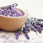Load image into Gallery viewer, Lavender bath salts in a wooden bowl with fresh lavender flowers on a woven mat