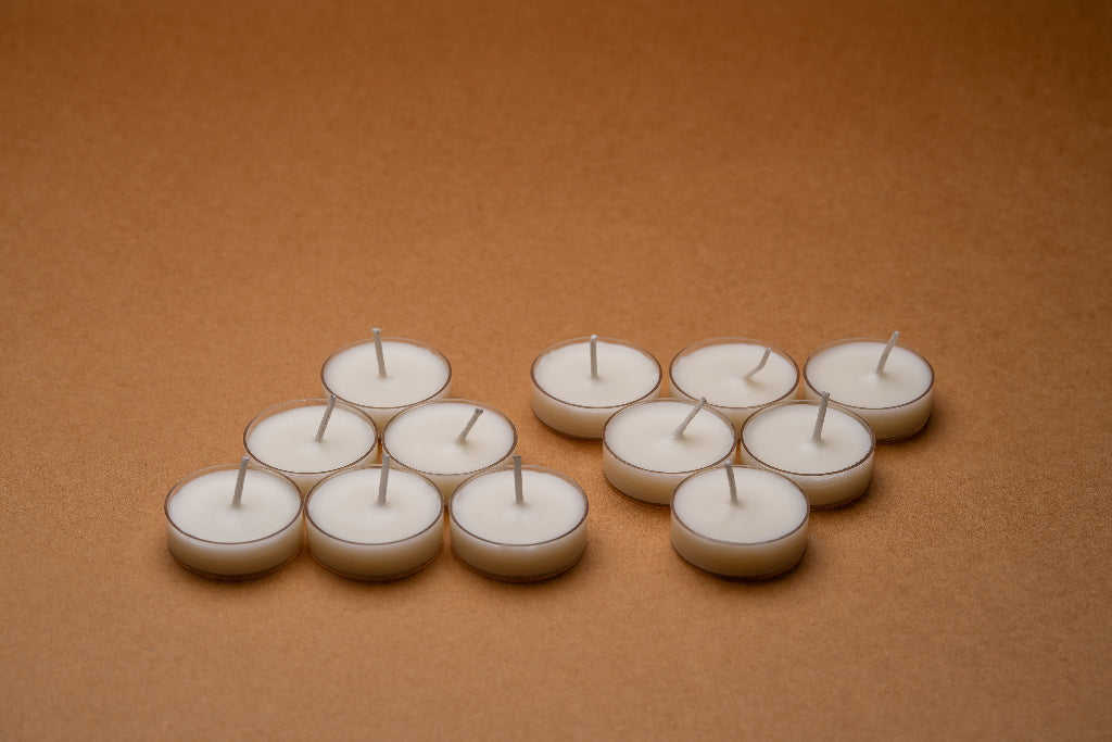White tealight candles arranged on a brown surface, minimalist decor setting