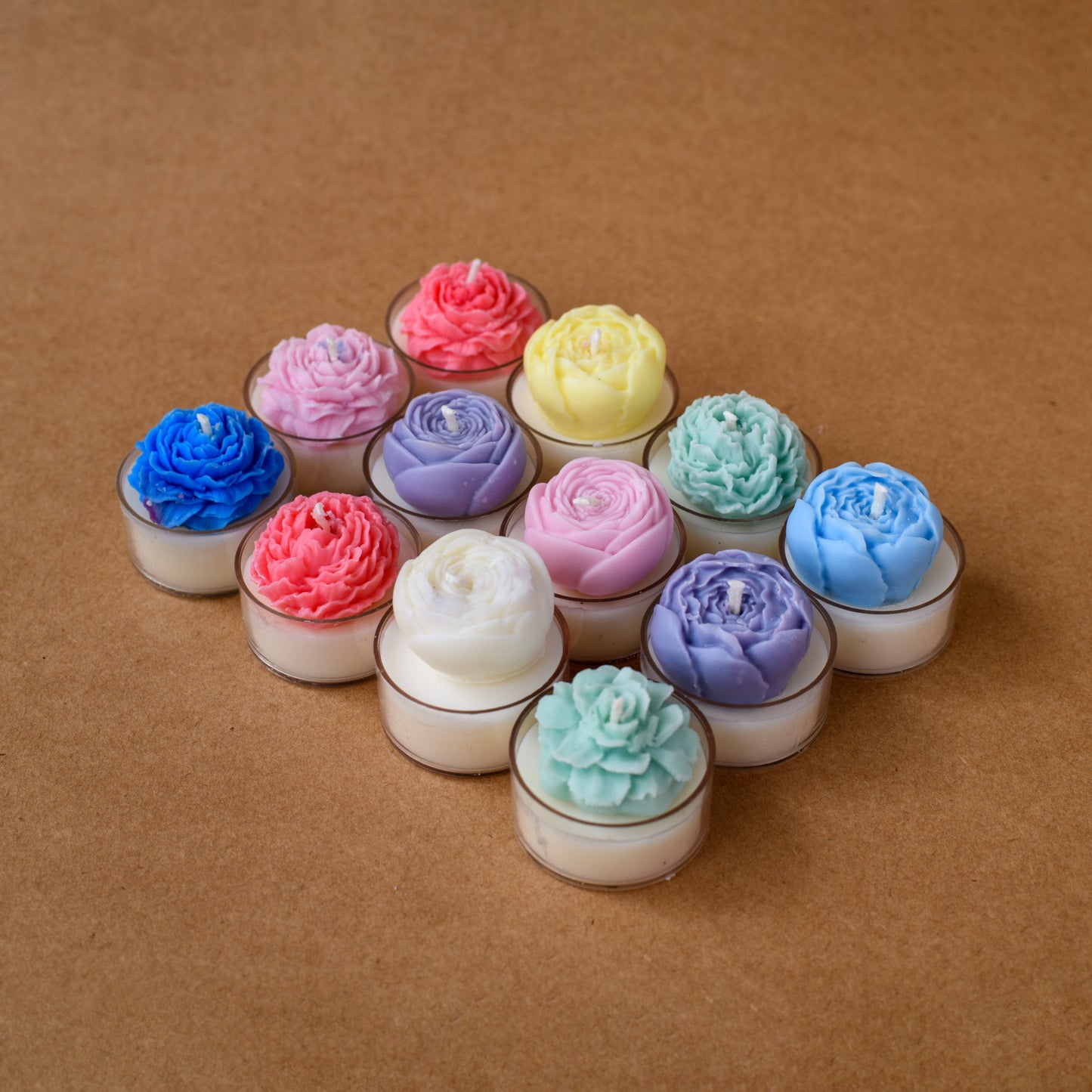 Colorful flower-shaped tealight candles arranged on a brown tabletop