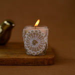 Load image into Gallery viewer, Handmade white lace-wrapped glass candle burning on wooden board, brown background