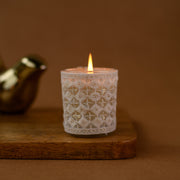 Lace-wrapped candle burning on wooden tray with brown background, cozy home decor