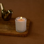 Load image into Gallery viewer, Lit decorative candle in a beaded holder on wooden tray with gold bird figurine