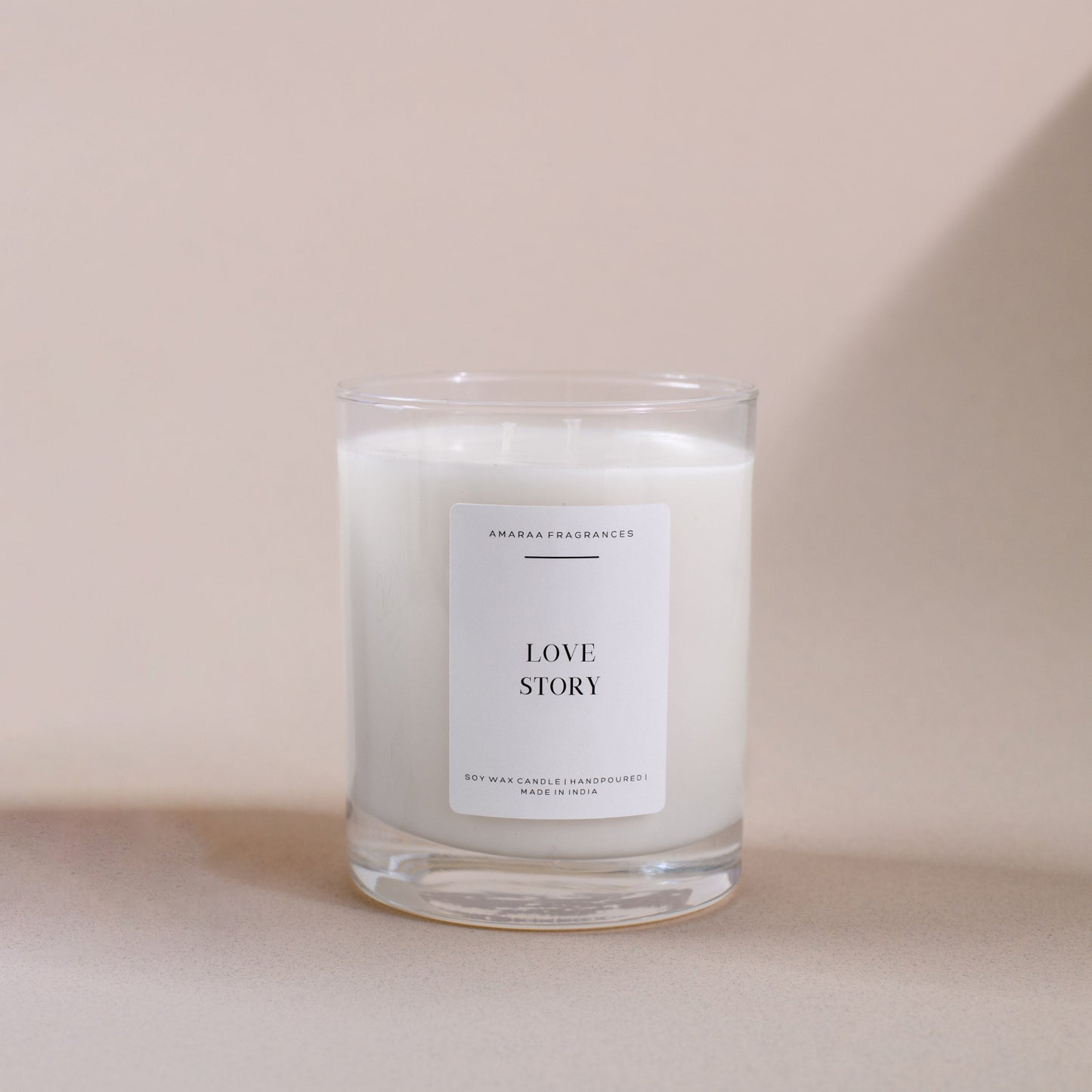 Amaraa Fragrances Love Story soy wax candle in clear glass on beige background