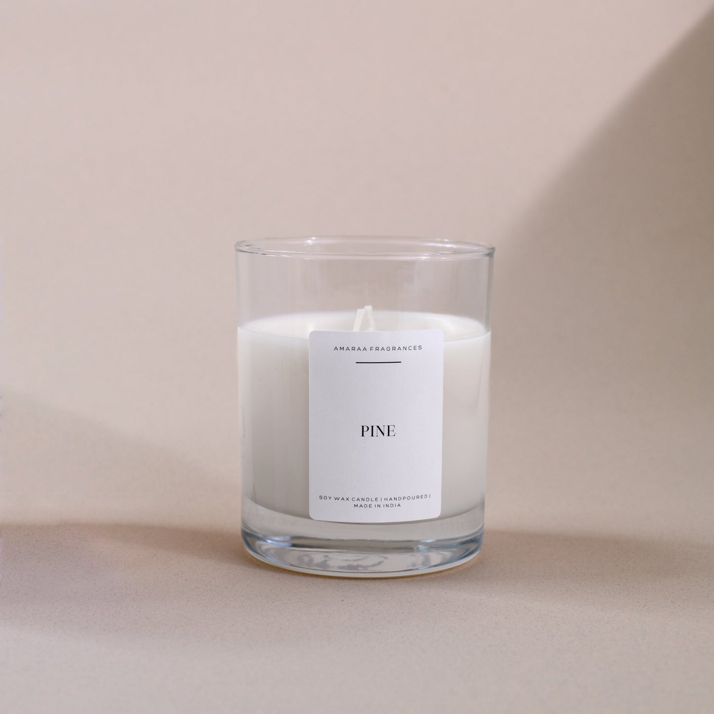 Pine soy wax candle in clear glass jar with minimalist label on beige background