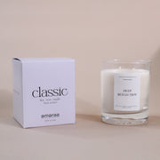 Classic soy wax candle in glass jar with Deep Reflection label and matching box on beige background