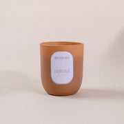Brown amaraa natural soy wax candle with label on neutral background