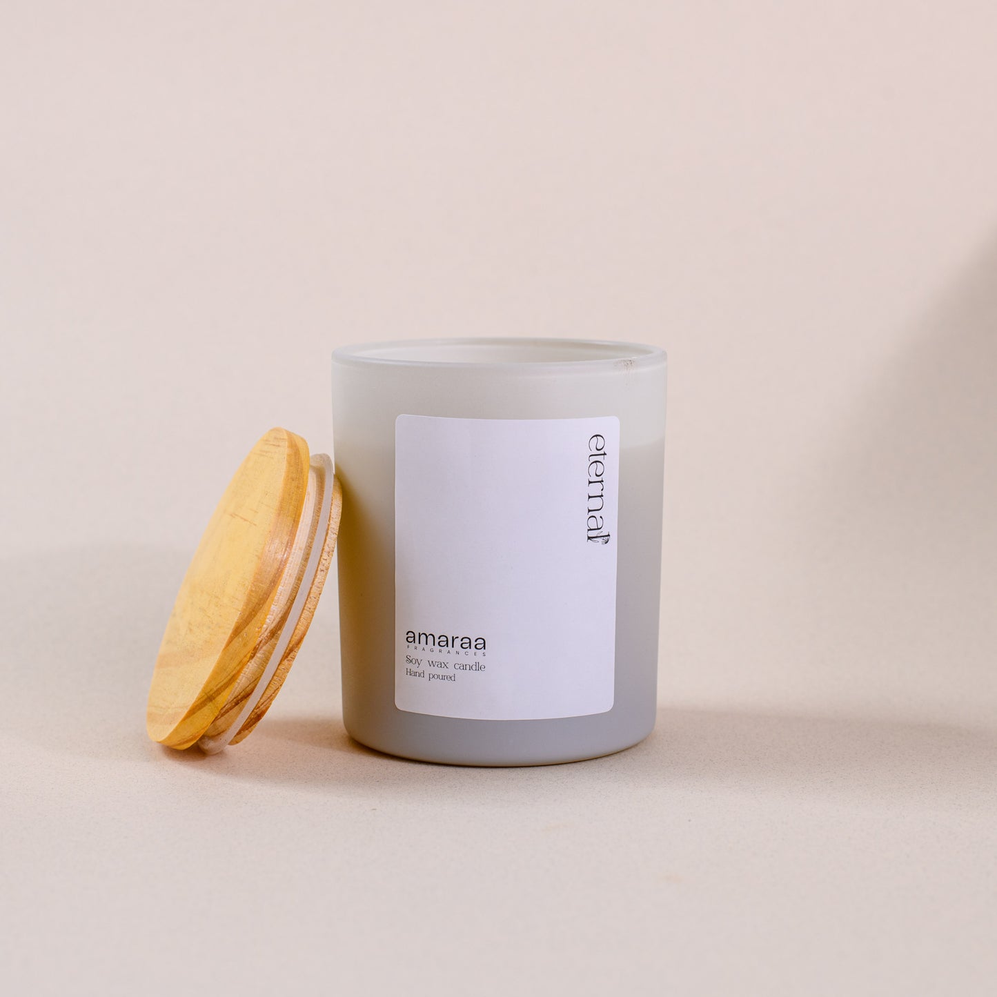 Minimalist soy wax candle in frosted glass jar with wood lid, amaraa scent, eternal label