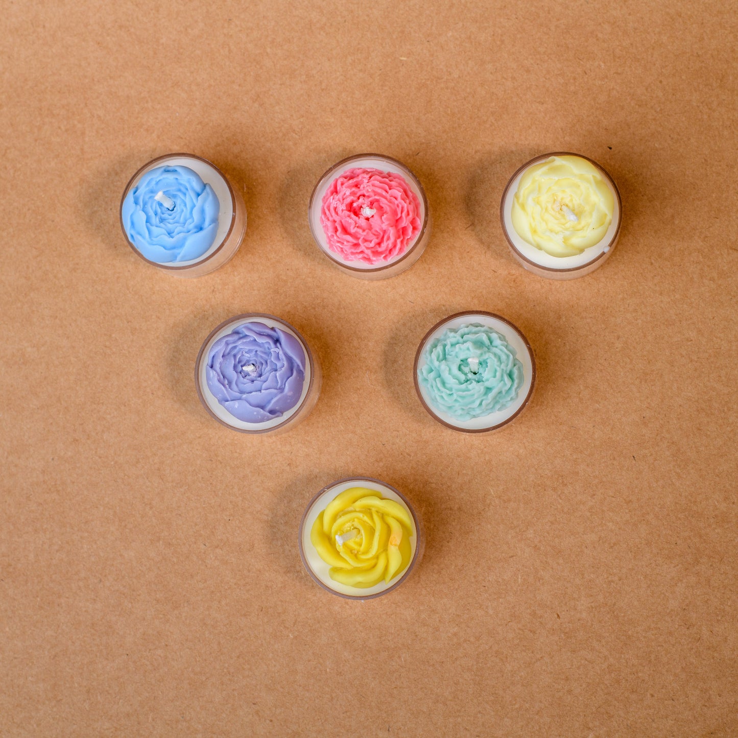 Colorful flower-shaped tealight candles arranged on a brown surface