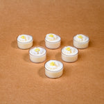 Load image into Gallery viewer, Six white tealight candles with daisy flower tops on a brown background