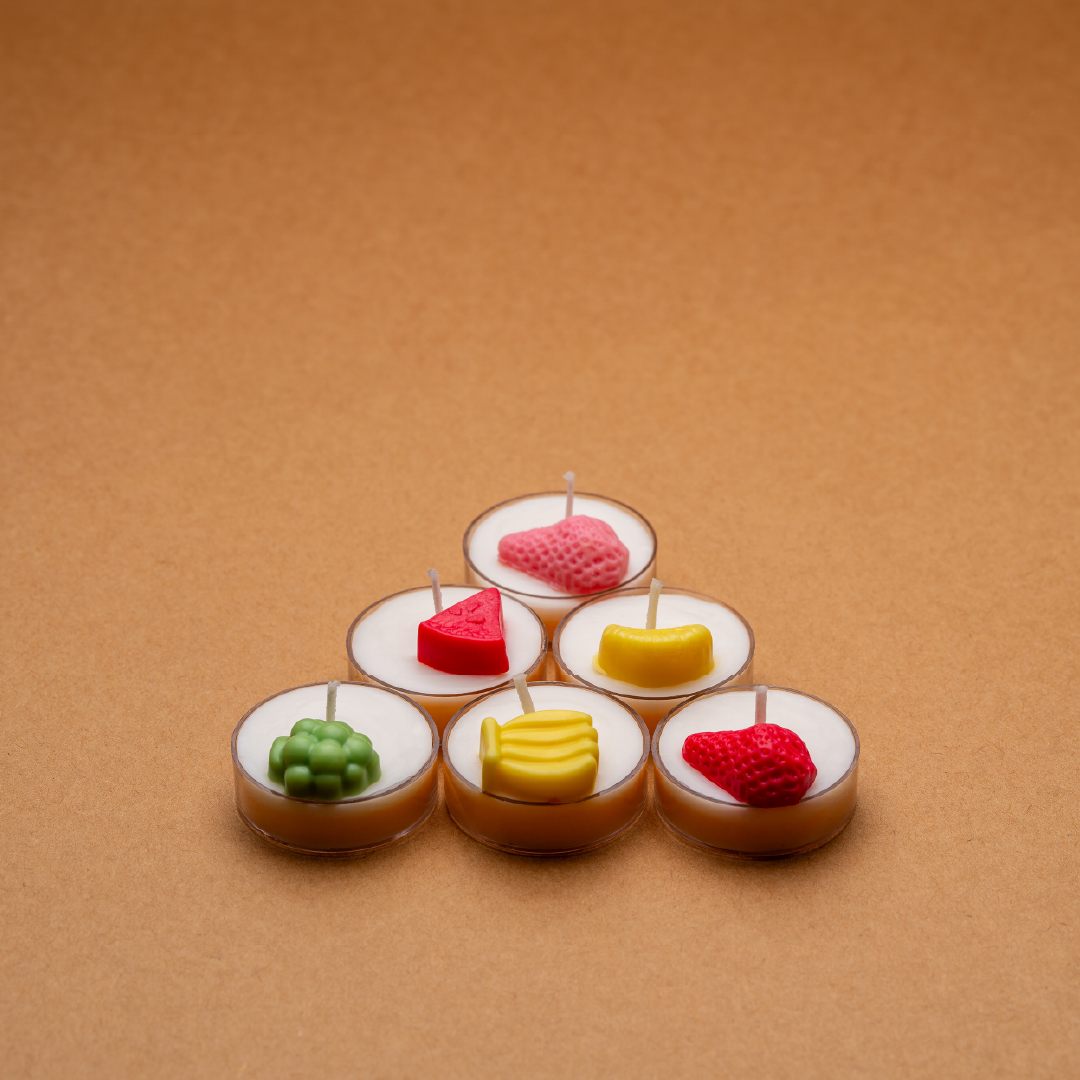 Colorful fruit-shaped tealight candles on a brown background