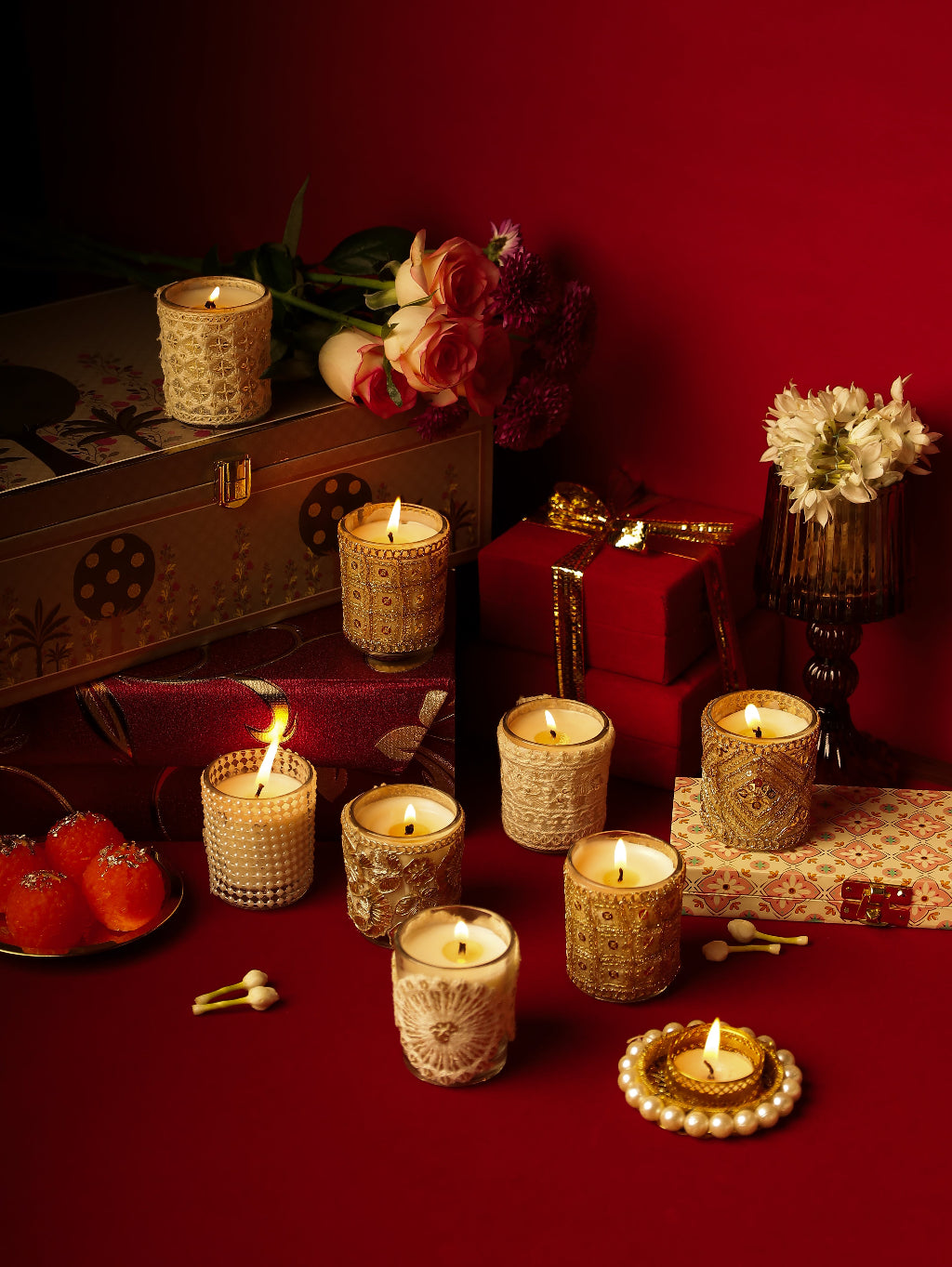 Decorative candles, flowers, gifts, and sweets on a red background for festive decor