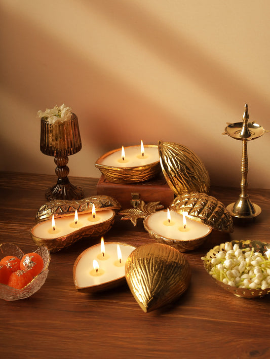 Decorative gold candles, flowers, sweets, and brass diya on wooden table for festive decor