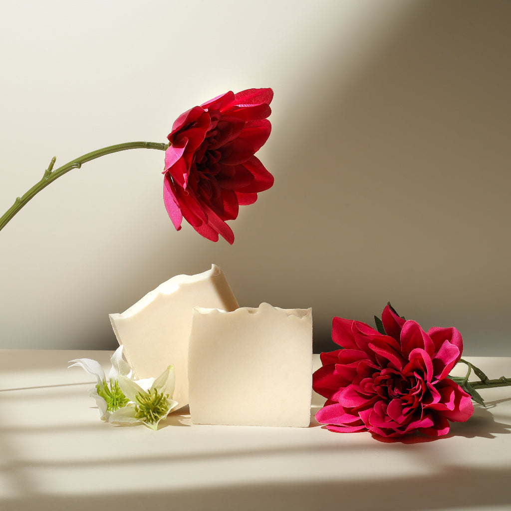 Handmade natural soap bars with pink flowers on a neutral background
