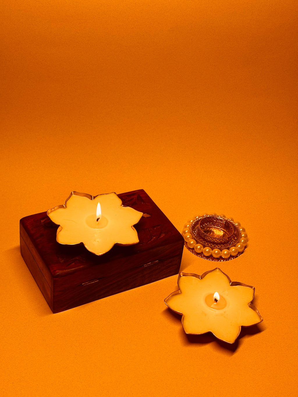 Lotus flower candles and decorative diya on yellow background for Diwali celebration