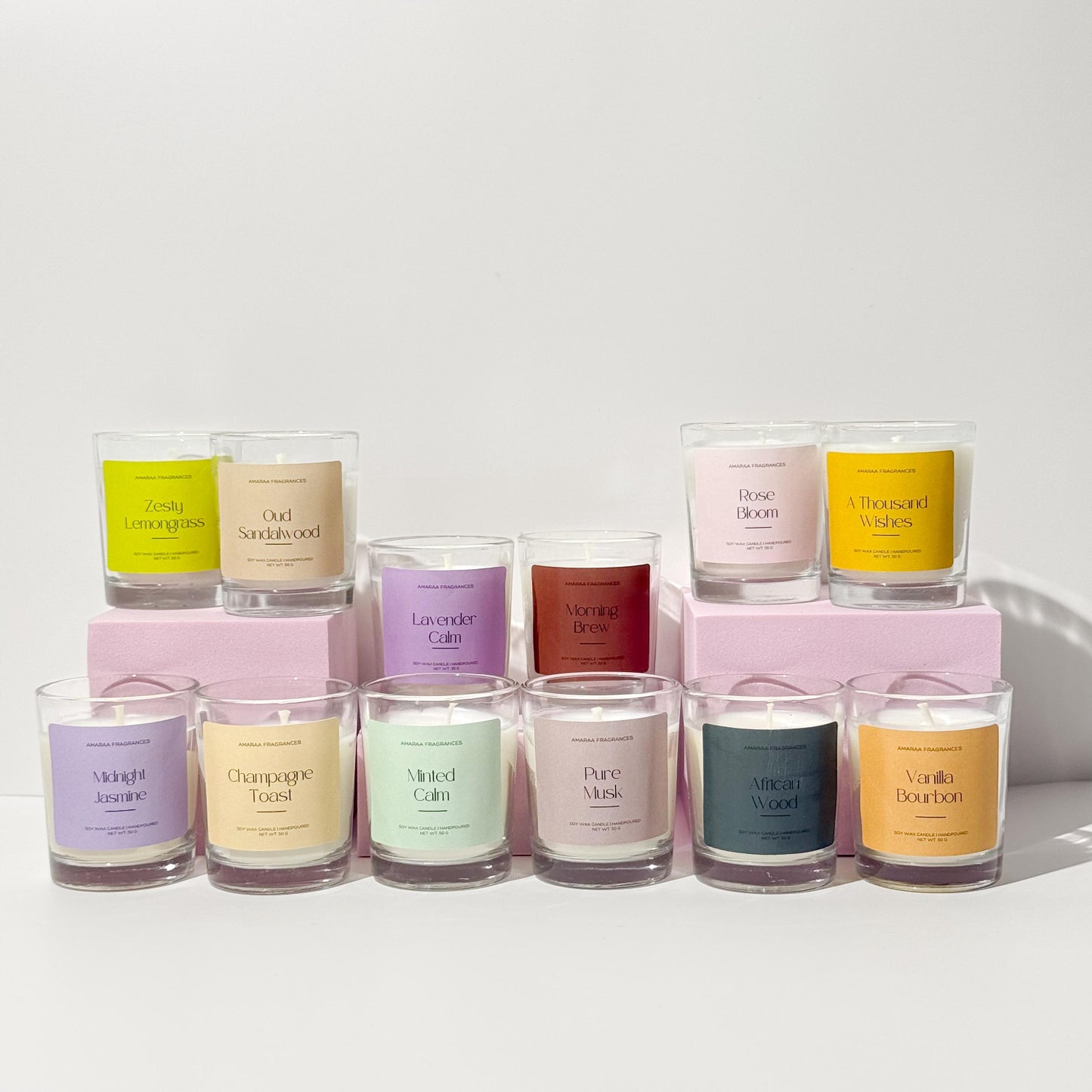 Assorted scented candles in glass jars with colorful labels displayed on a white background
