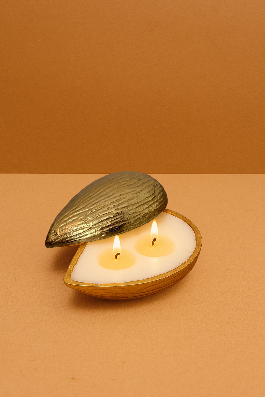 Decorative almond-shaped gold candle with two flames on a beige background