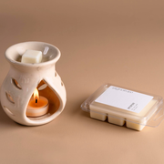 Ceramic wax melt burner with lit tealight and wax melts on beige background