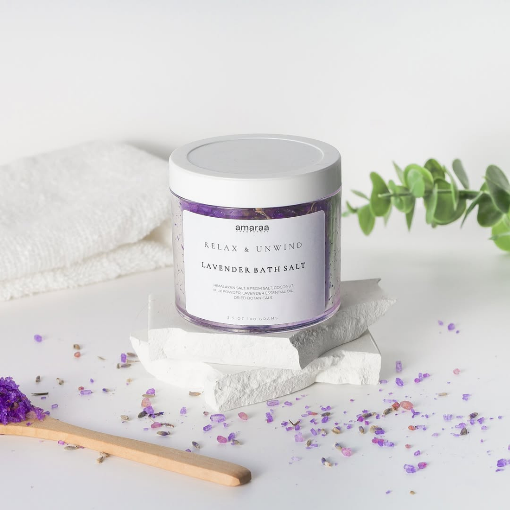 Amaraa lavender bath salt jar with purple crystals, wooden spoon, towel, and green sprig