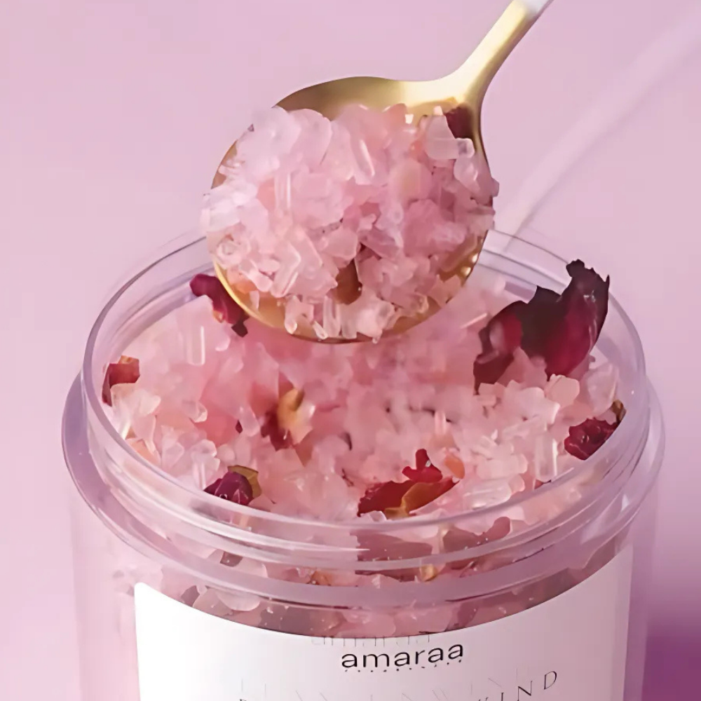 Pink bath salts with rose petals in clear jar and gold spoon, spa self-care product