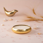 Load image into Gallery viewer, Gold bowl candle with three wicks, decorative stones, wheat, and gold bird on beige background