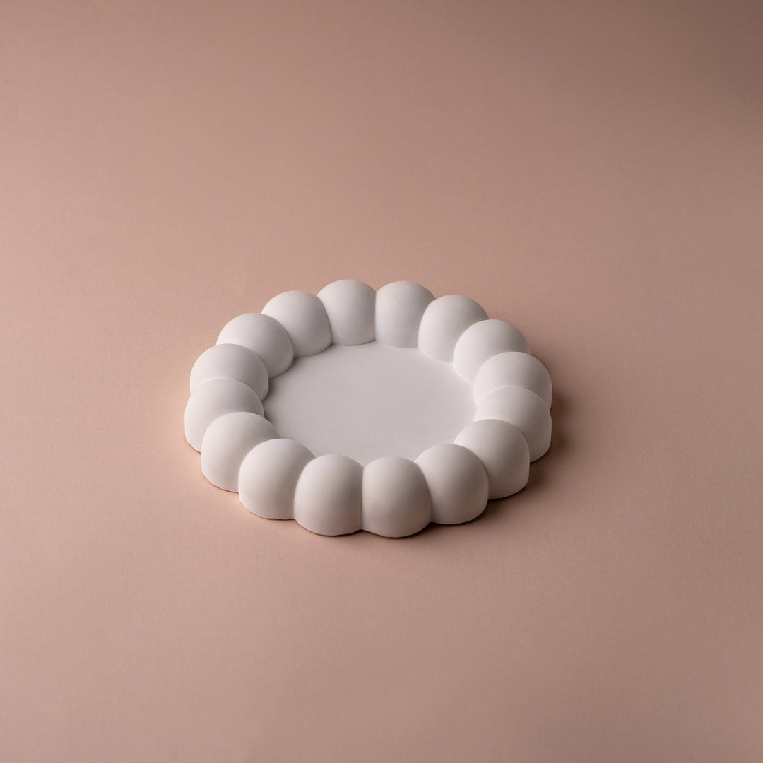 Modern white bubble edge ceramic plate on a beige background