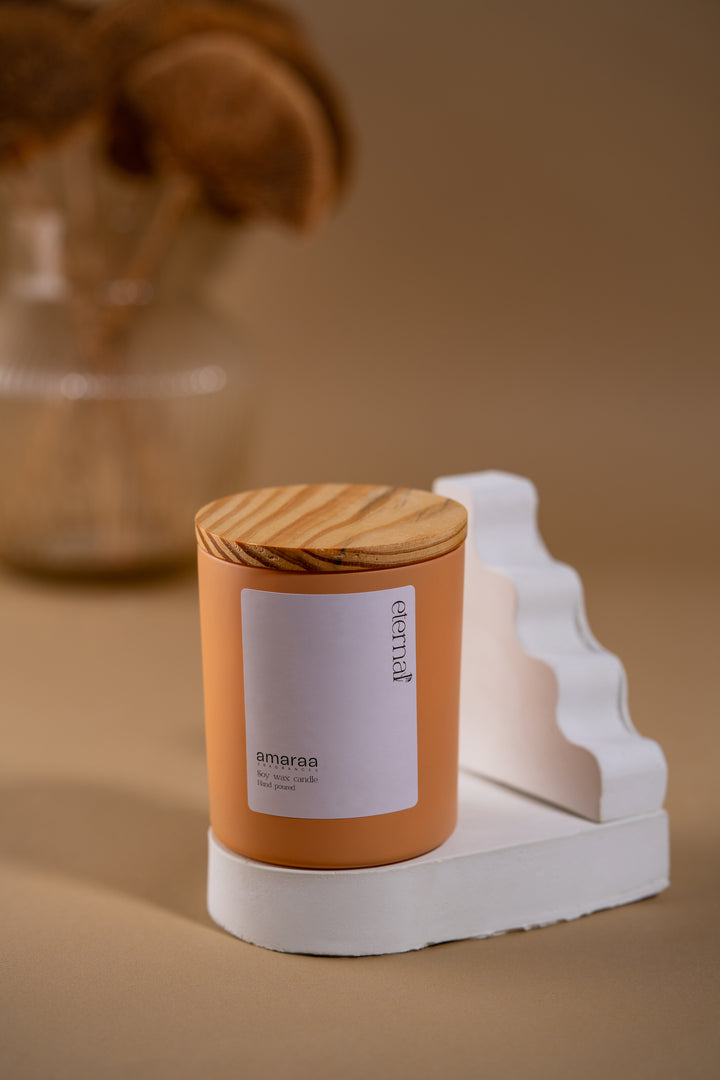 Amaraa soy wax candle with wooden lid on white stand, minimalist beige background, decor