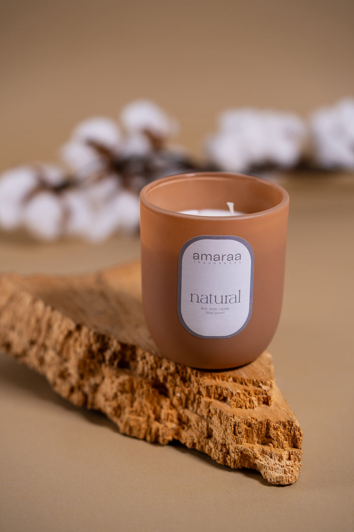 Amaraa natural soy wax candle in brown glass jar on cork, cotton flowers in background