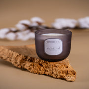 Amaraa natural soy wax candle in frosted glass on cork, cotton plant in background