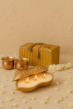Load image into Gallery viewer, Decorative brass cups, gold candle, yellow gift box, and jasmine flowers on beige background