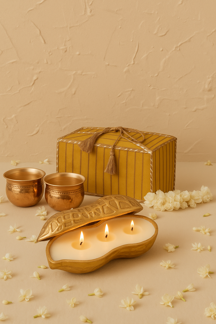 Decorative brass cups, gold candle, yellow gift box, and jasmine flowers on beige background