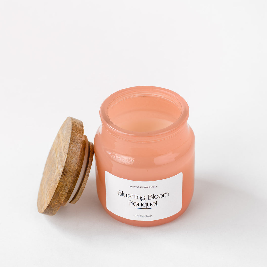 Blushing Bloom Bouquet scented candle in pink glass jar with wooden lid on white background