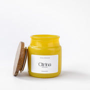 Yellow Citrina scented candle in glass jar with wooden lid on white background