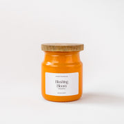 Orange Blushing Bloom scented candle jar with wooden lid on white background