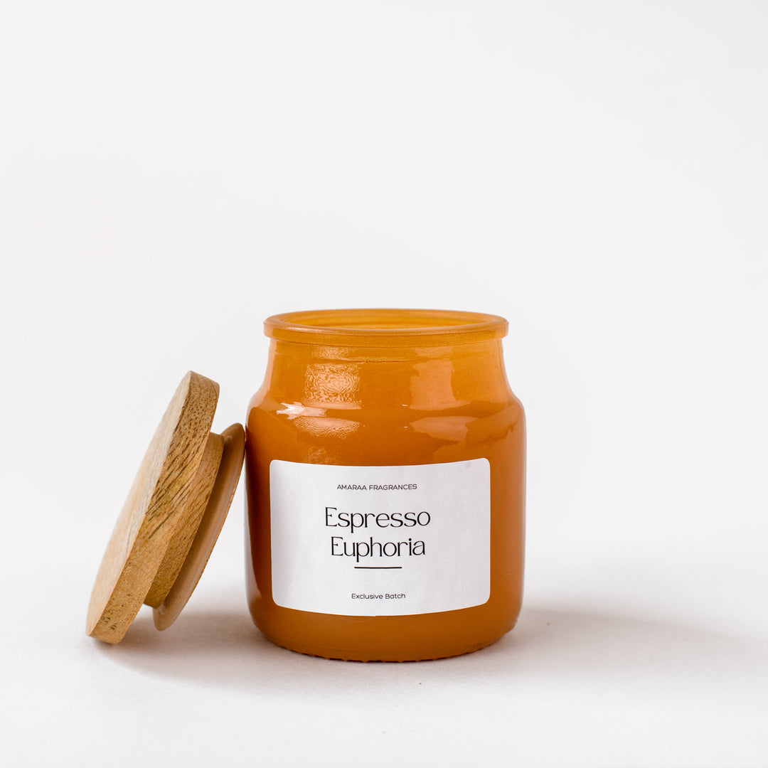Amber glass candle jar labeled Espresso Euphoria with wooden lid on white background