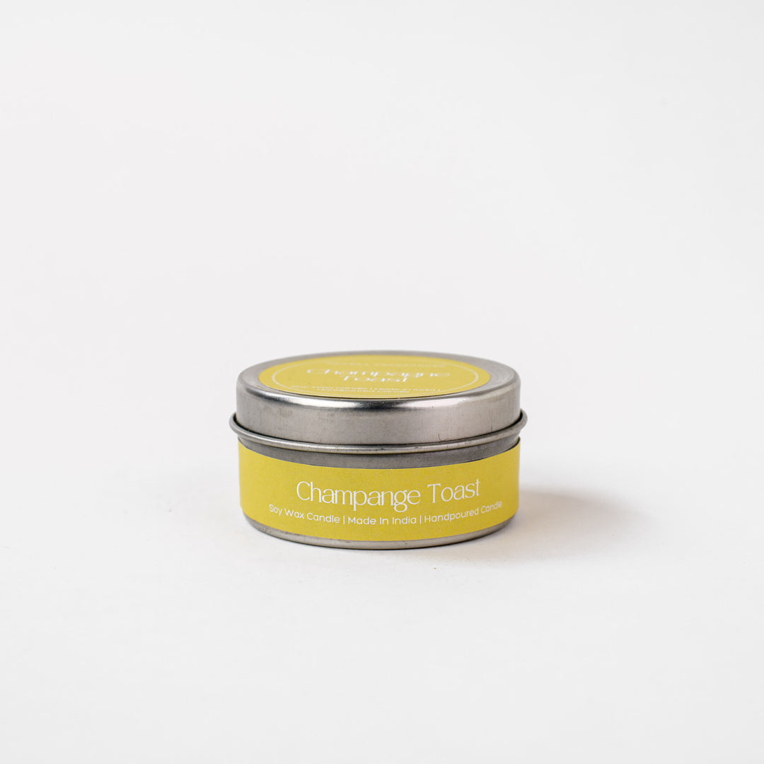 Champagne Toast soy wax candle in a small metal tin with yellow label on white background