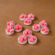 Pink heart-shaped tealight candles arranged on a brown surface for decoration