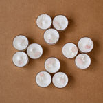 Load image into Gallery viewer, white tealight candles with rose quartz and clear crystals on brown background