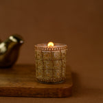Load image into Gallery viewer, Decorative gold glass candle holder with lit candle on wooden board, brown background