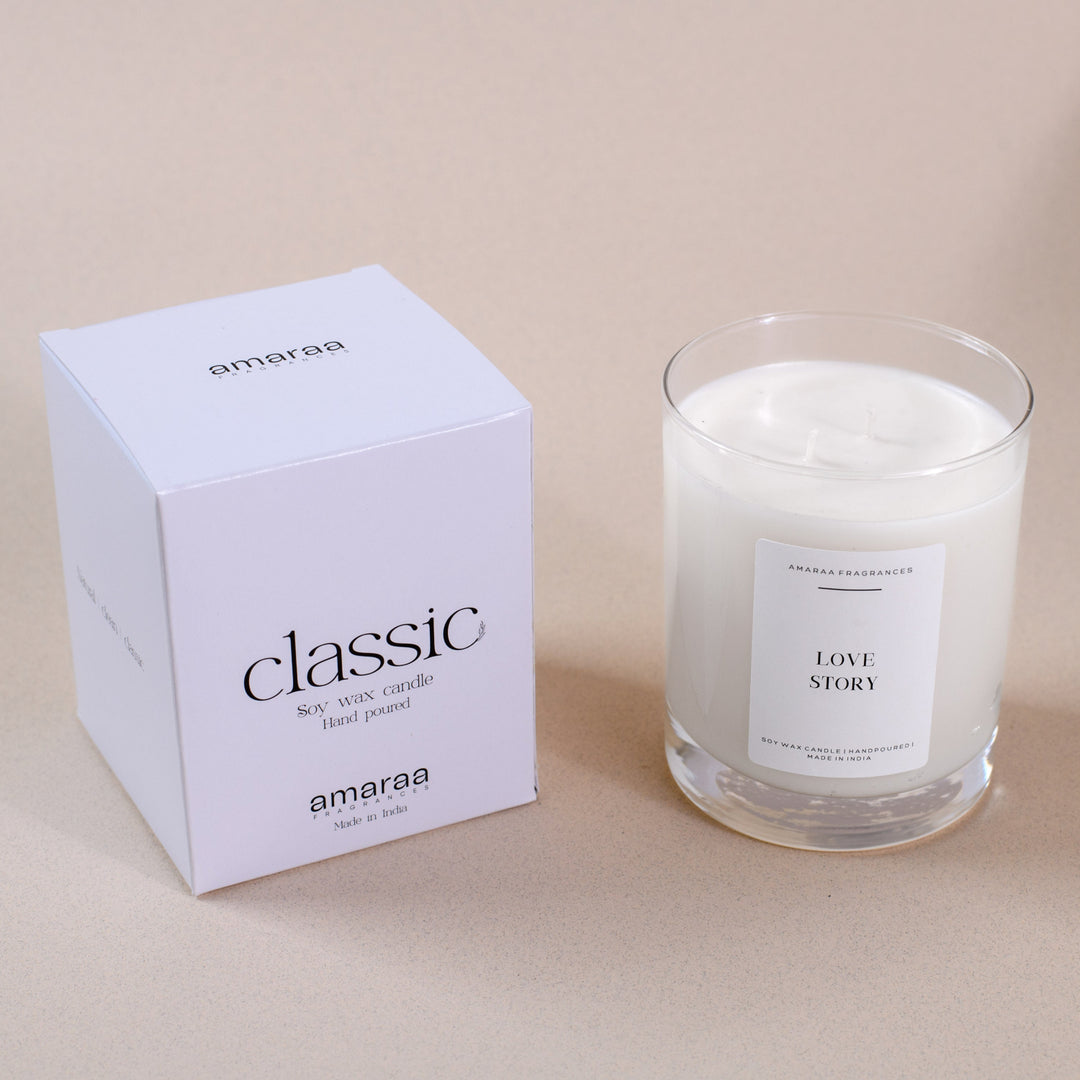 Amaraa classic soy wax candle in glass with white box, labeled Love Story, on beige surface