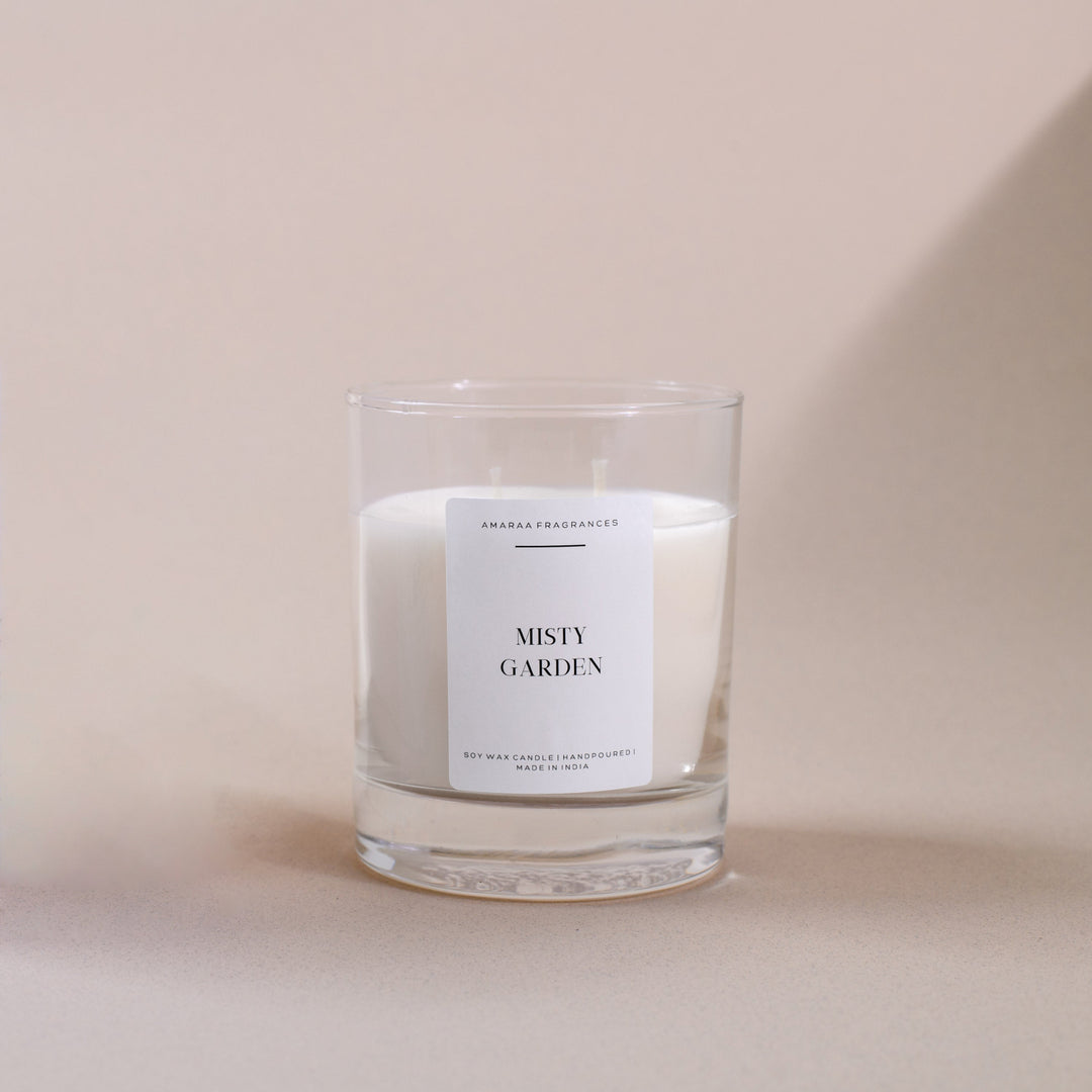 Amaraa Fragrances Misty Garden soy wax candle in clear glass jar on beige background