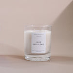 Load image into Gallery viewer, Clear glass soy wax candle labeled 'Deep Reflection' by AMARAA Fragrances on beige background.