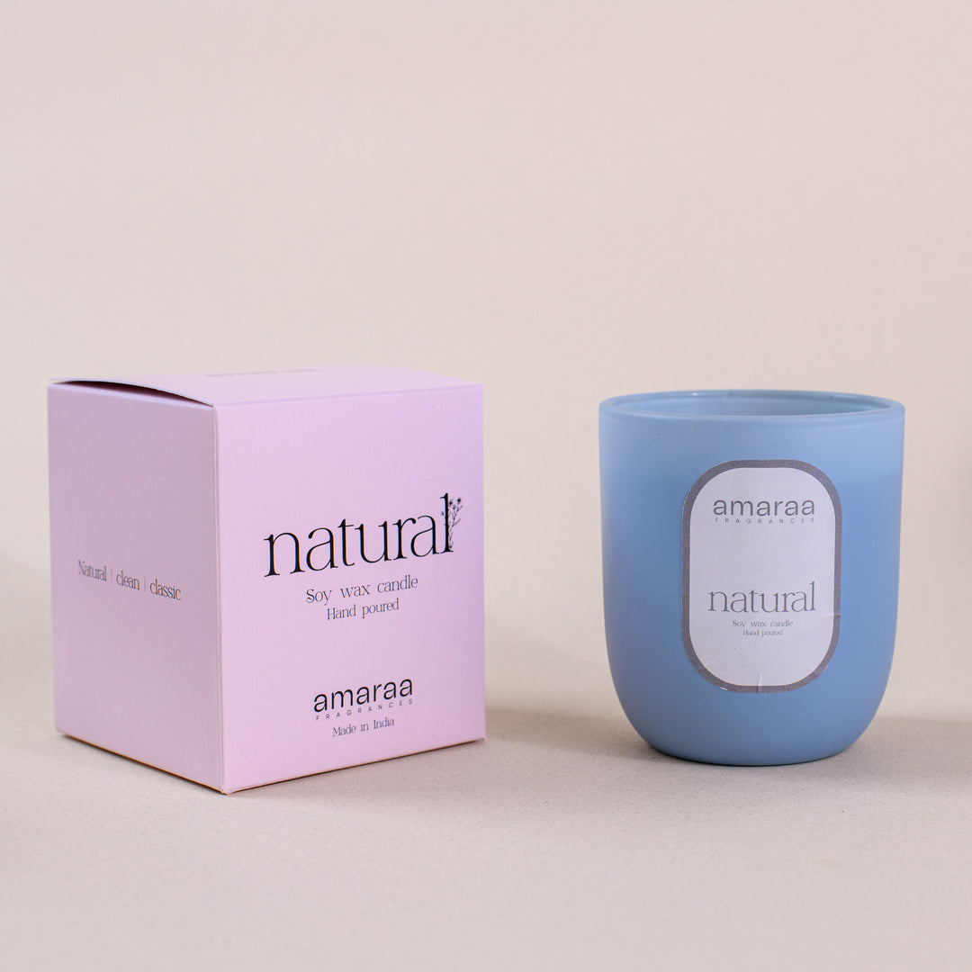 Blue amaraa natural soy wax candle with pink box on beige background