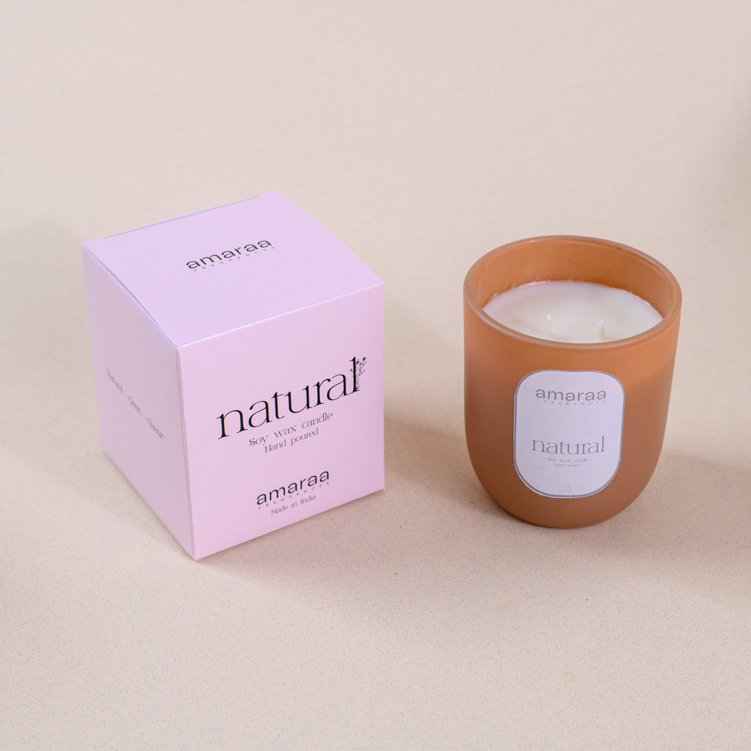 Amaraa natural soy wax candle in brown glass jar with pink box on beige background