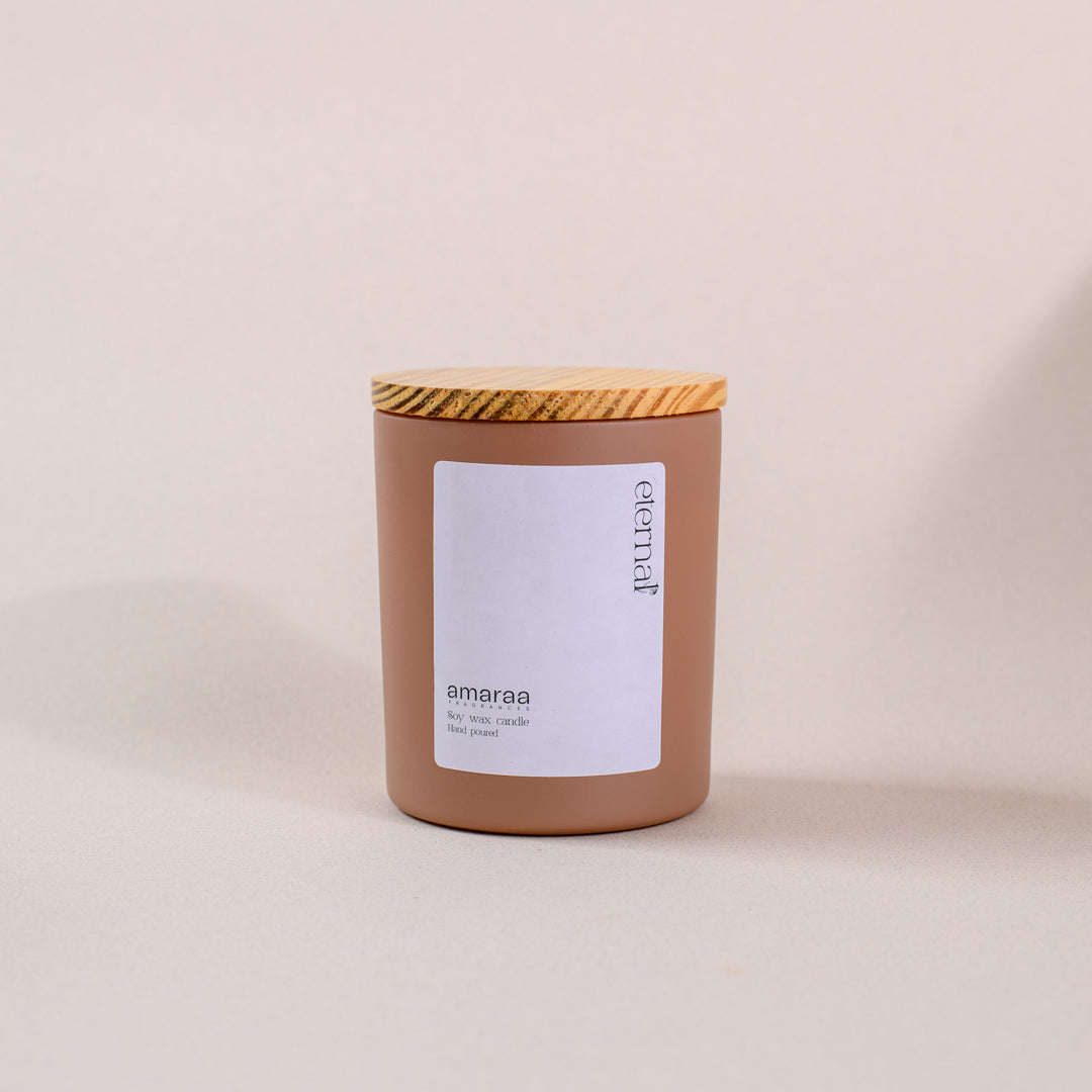 Brown jar amaraa soy wax candle with wood lid on neutral background