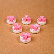 Six tealight candles with pink heart shapes on brown background